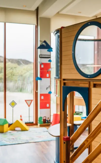 Indoor playroom with a play structure near a window.