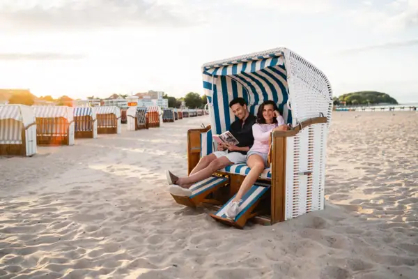 A man and a woman are sitting in a beach chair.