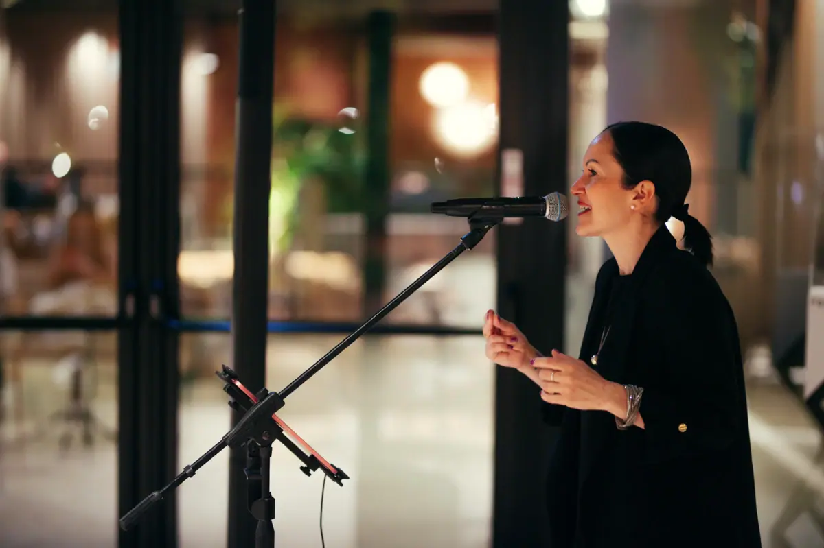 A woman speaking into a microphone at a concert.