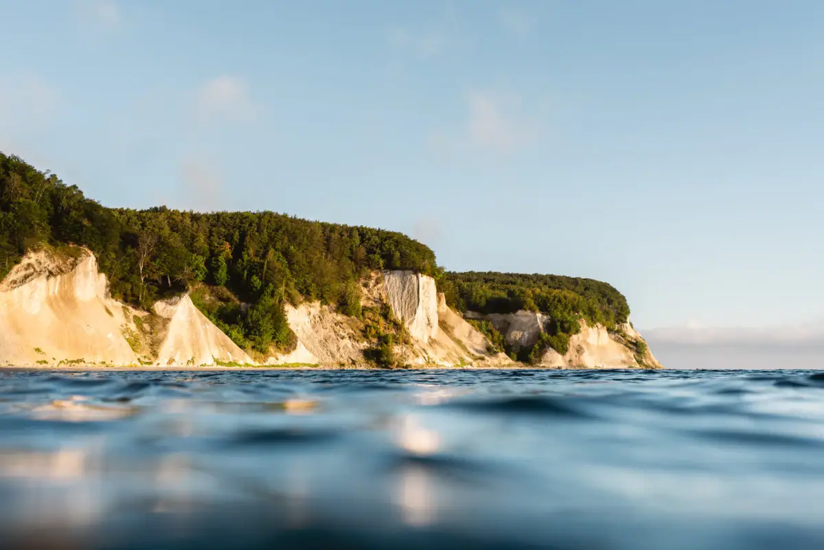 Ein Gewässer mit einer Klippe und Bäumen.