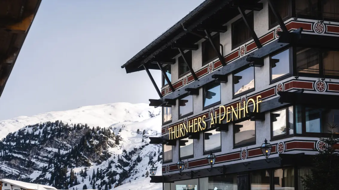 A building with a sign on the front, surrounded by snow-covered mountains.