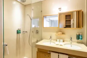 Bathroom with shower and washbasin, equipped with modern fittings and tiles.