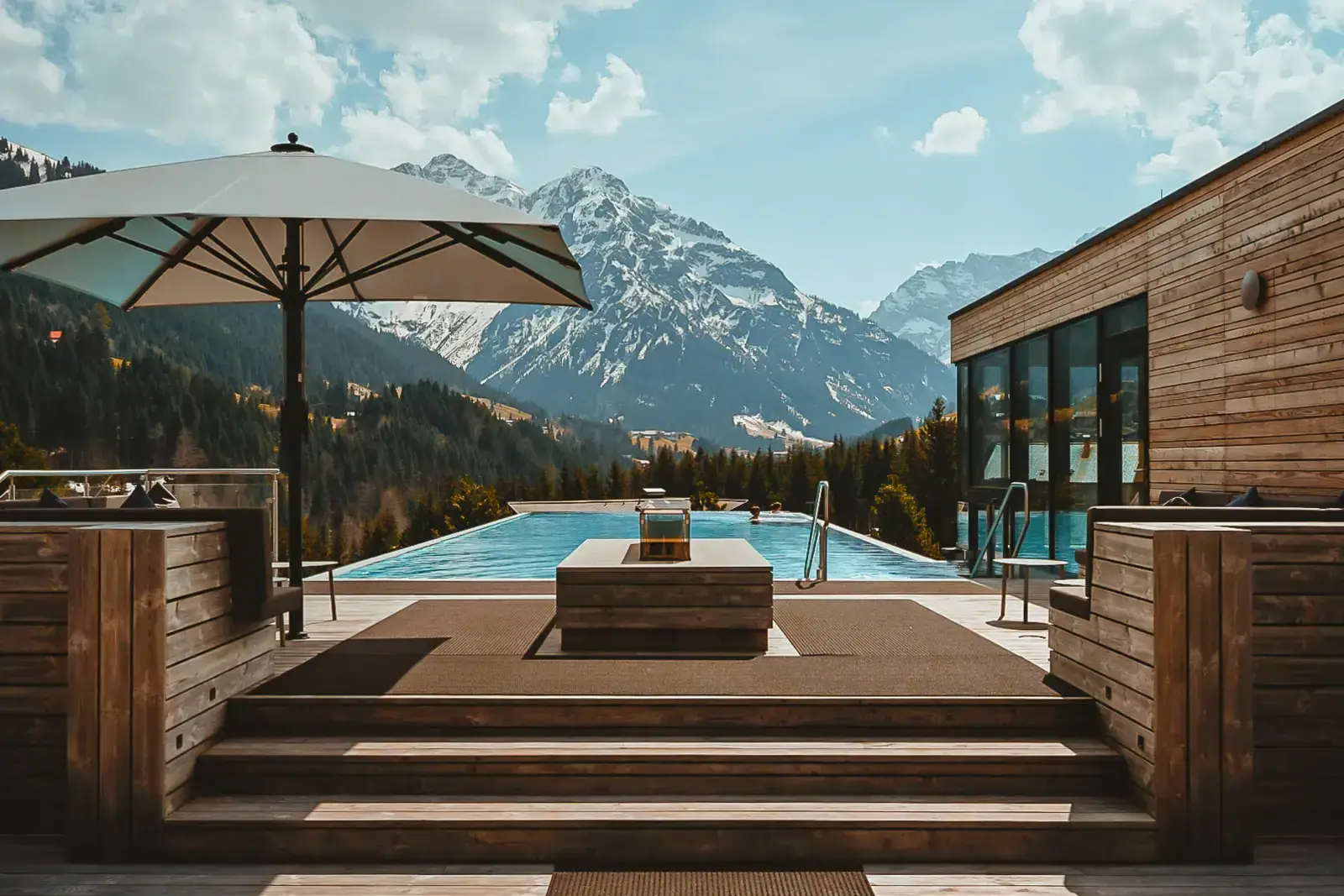 Pool mit Holzdeck und großem Sonnenschirm im Freien.