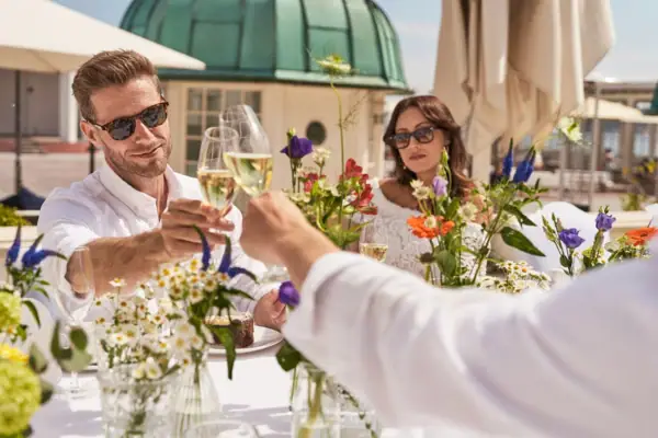 A group of people sitting at a table with flowers and drinks.