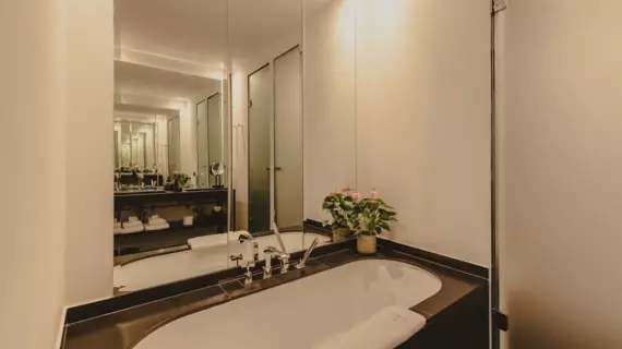 A bright, elegant bathroom with bathtub and mirror behind it. 