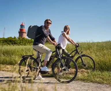 A man and a woman are cycling along a path.