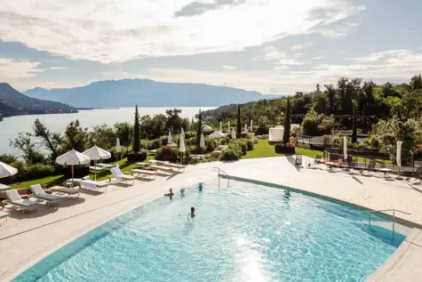 Aerial view of a luxurious outdoor pool with people swimming and loungers around it. 