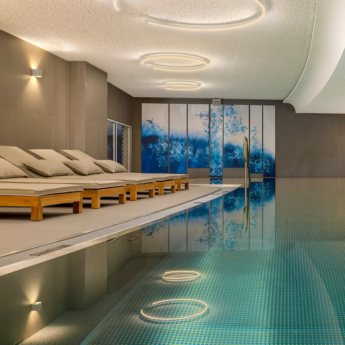 An indoor swimming pool with a large terrace and sun loungers.