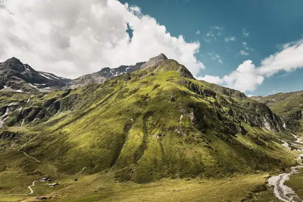 Grüner Berg mit Grasfläche unter einem blauen Himmel.